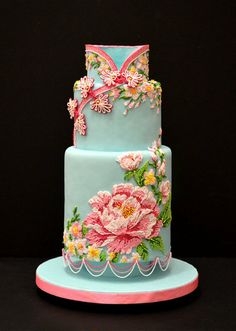 a three tiered blue cake with pink flowers on it