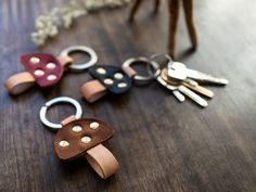 four leather keychains sitting on top of a wooden table