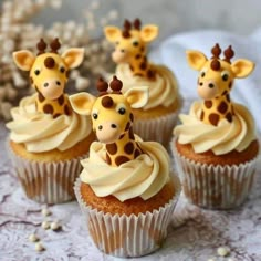 cupcakes decorated with giraffe heads and icing on a lace tablecloth