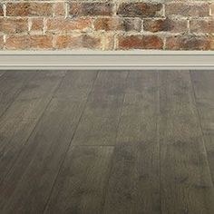 an empty room with brick wall and wood flooring