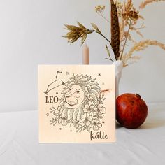 a wooden card with an image of leo the lion on it next to a plant