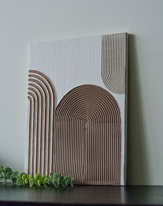 a wooden block with lines and circles on it next to a plant in front of a white wall