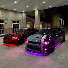 two cars parked in front of a building with purple lights on the side of it