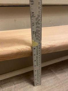 a measuring ruler sitting on top of a wooden table next to a window sill