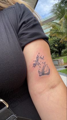 a woman's arm with a tattoo that has a book and flowers on it