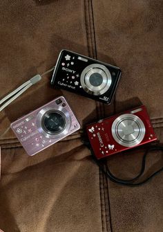 two cameras sitting next to each other on a bed