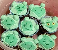 cupcakes with green frosting in a plastic container on top of a table