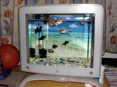 an old television with fish in it on a table next to a basketball and cd's