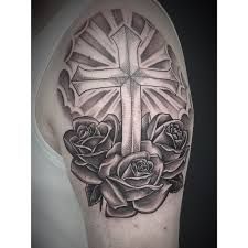 a cross and roses tattoo on the arm