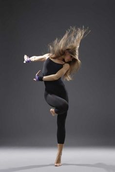 a woman is jumping in the air with her hair blowing