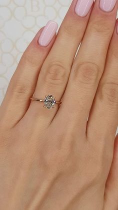 a woman's hand with pink manicured nails and a diamond ring