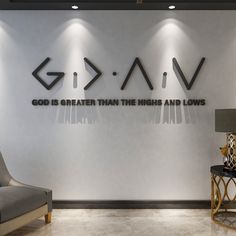 a room with a chair, lamp and wall art on the wall that says god is greater than this and lows