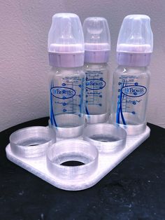 three baby bottles sitting on top of a plastic tray