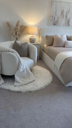 a white bed sitting next to a chair in a bedroom on top of a carpeted floor