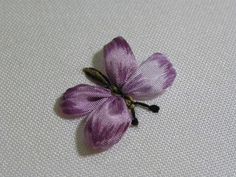 a small purple flower sitting on top of a white cloth