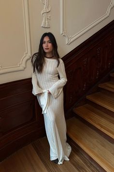 a woman is standing on the stairs in a white dress