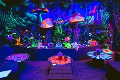 an indoor garden with colorful lights and plants on the ground, including mushrooms in the background