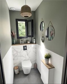 a white toilet sitting next to a window in a bathroom