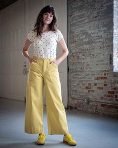 a woman standing in an empty room with her hands on her hips and wearing yellow shoes