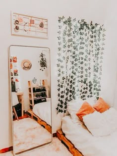 a mirror sitting next to a bed in a room with white walls and wooden floors