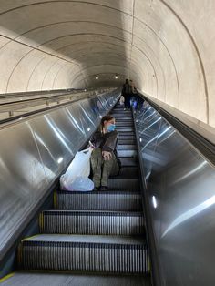 an escalator with people walking down it and carrying bags on each handrail