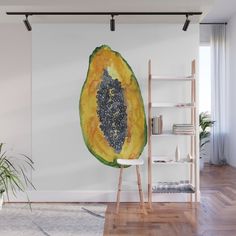 a large piece of fruit on a wall in a room with wooden flooring and white walls