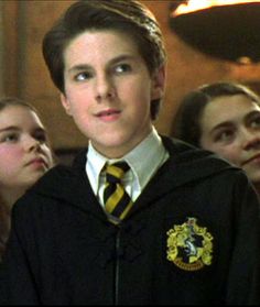 the young harry potter is standing in front of some other people and looking at something