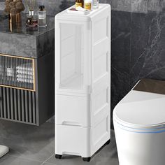 a white cabinet next to a toilet in a bathroom with grey walls and tile flooring