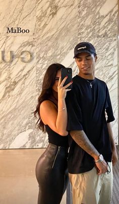 a man and woman taking a selfie in front of a marble wall with the word gucci on it