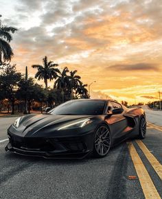 a black sports car is parked on the side of the road in front of palm trees