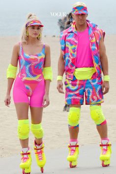 two people in neon colored clothing and roller skates on the beach with one person wearing bright yellow knee pads