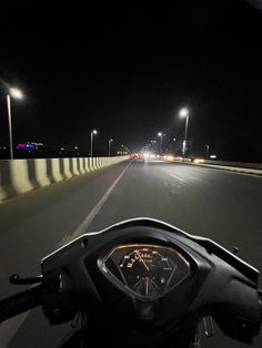 a motorcycle is driving down the road at night with its headlights on and it's lights turned on