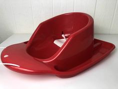 a red baby potty sitting on top of a white table