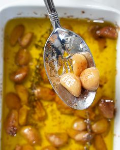 a spoon with some food in it on top of a dish filled with oil and seasonings