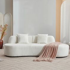 a white couch sitting on top of a floor next to a mirror in a living room