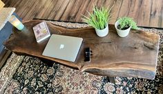 a wooden table topped with a laptop computer and potted plants on top of it