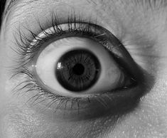 an eye is shown with long eyelashes and black - and - white image in the background