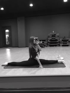 a woman sitting on top of a yoga mat while talking on a cell phone in a gym