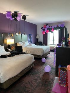 two beds in a hotel room with balloons on the ceiling and decorations hanging from the ceiling