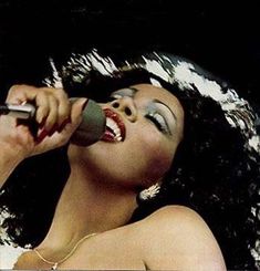 a woman singing into a microphone with her mouth open