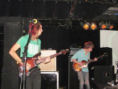 two people are playing guitars on stage