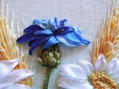 three different colored flowers on a white cloth