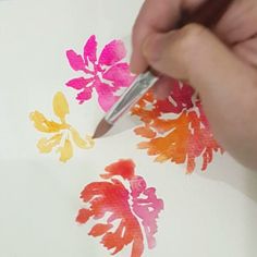 someone is painting flowers with watercolors on paper