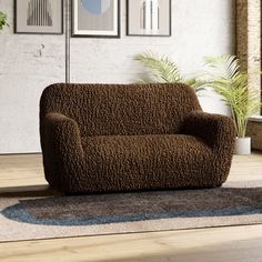 a brown couch sitting on top of a wooden floor next to a potted plant