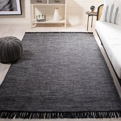 a black and white rug with fringes on the floor in front of a couch