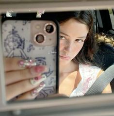 a woman taking a selfie with her cell phone in the back seat of a car