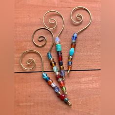 three colorful beaded necklaces are on a wooden table with metal wire and beads