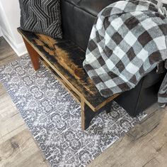 a black leather couch sitting on top of a wooden floor next to a white rug