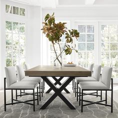 a dining room table with six chairs and a potted plant in the middle on top