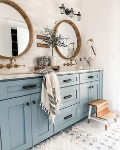 a bathroom with blue cabinets and two round mirrors